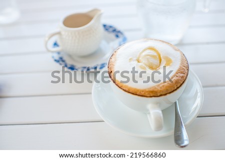 Coffee mug with syrup on white wooden table.