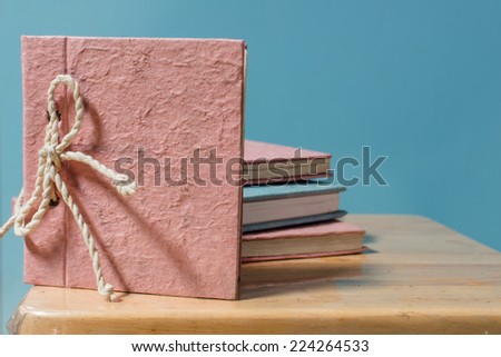 Pink handmade notebook made from mulberry paper with blue pastel background.
