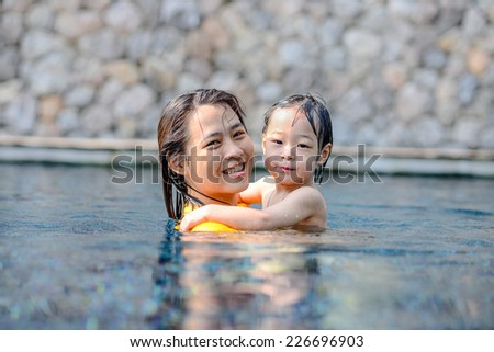 Happy Asian sister and child in swimming pool.