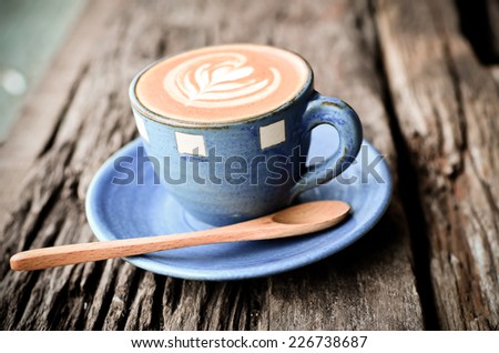 Latte art, Blue coffee cup on wooden background with vintage colour effect.