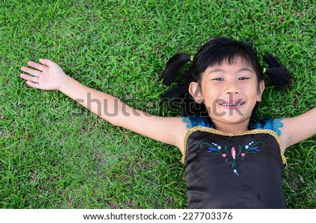 Asian girl lying on grass hand rise her hand.