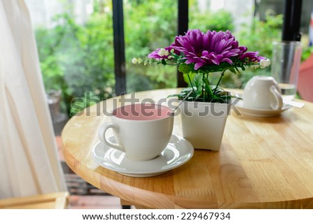 Coffee mug and flower pot on wooden table.