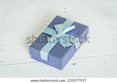 Blue gift box on wooden table, vintage picture style.