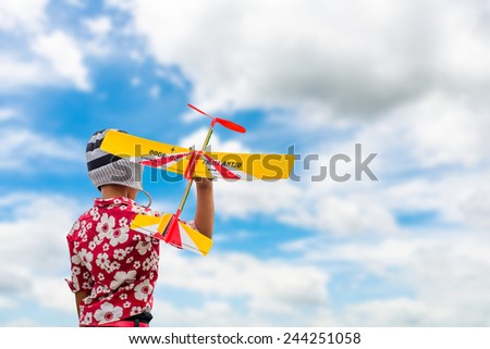 Boy in Knitting hats playing with a toy airplane with blue sky.