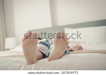 Young kid bare feet in bed with vintage tone, dept of field.