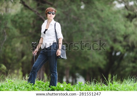Asian woman holding camera pole in her hand in the forest.