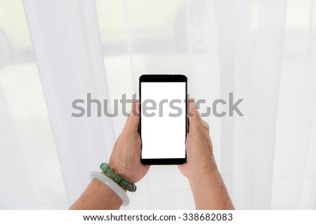 Senior woman hand with smart phone with white curtain background.