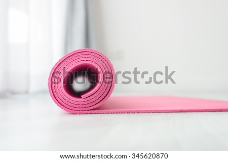 Pink yoga mat on gray floor at home.  Health concept.