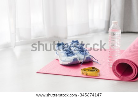 Sport shoes, yoga mat, bottle of water and centimeter on wooden background. Sport equipment. Concept healthy life. Selective focus