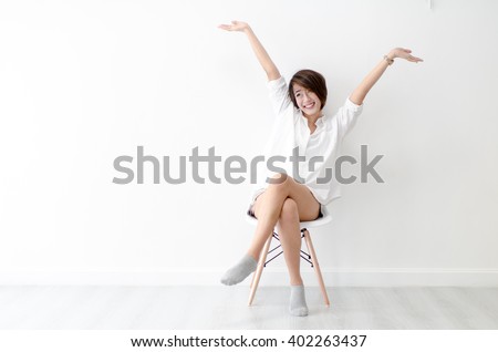 Attractive Asian girl sitting on white modern chair and relax at home.
