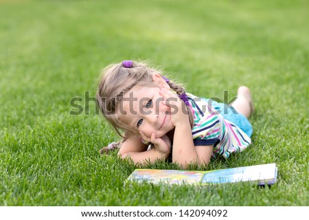 Adorable Little Girl Reading Book In The Garden - Outdoor
