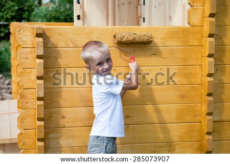 Cute blond boy painting the wall