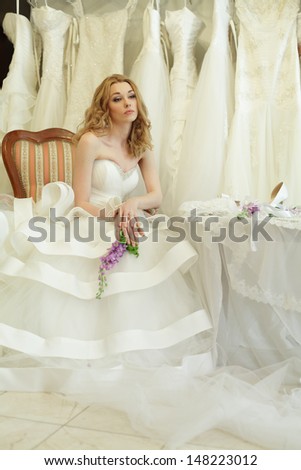 Beautiful bride in luxury interior on background of wedding dresses, vintage glamour style
