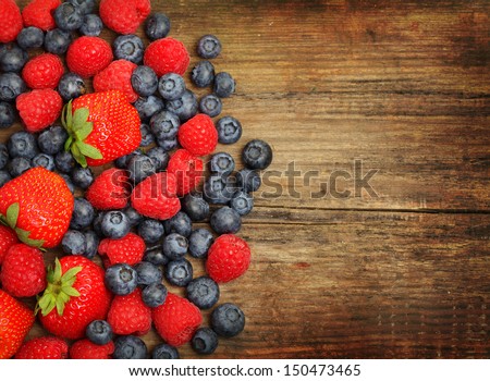 Organic berries on wooden background - summer and spring harvest, strawberries, raspberries, blueberry