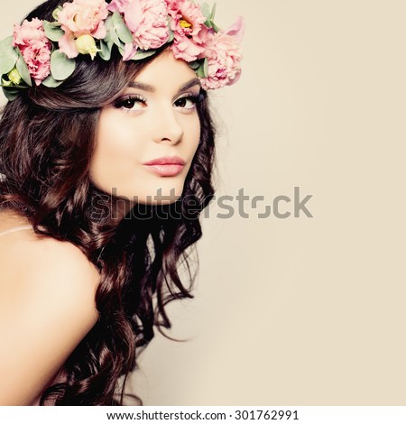 Beautiful Young Woman with Summer Pink Flowers. Long Permed Curly Hair and Fashion Makeup. Beauty Girl with Flowers Hairstyle.