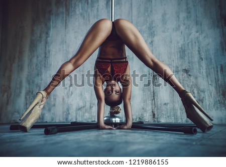 Young sexy slim woman pole dancing in vintage style interior on stone wall background