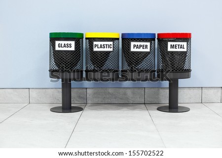 Four garbage bins on wall background.