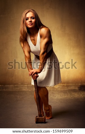 Young woman bodybuilder with hammer. Ancient style.