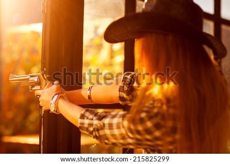 Young woman cowboy shooting. Focus on gun.