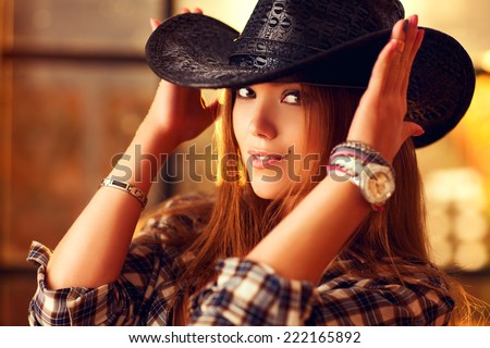 Young woman cowboy indoors portrait.