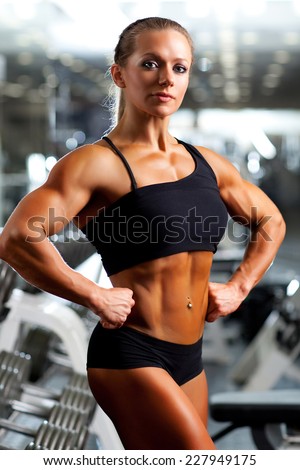Young woman bodybuilder with dumbbell.