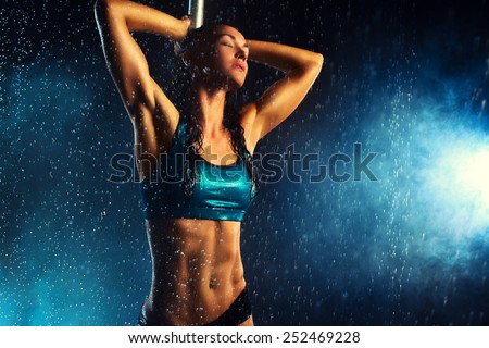 Young slim sexy brunette pole dance woman. Water rain effect.
