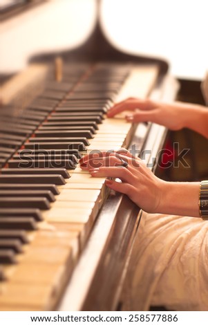 Young woman playing piano. Hands close-up view.