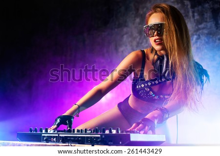 Young sexy woman dj playing music. Headphones and dj mixer on table.