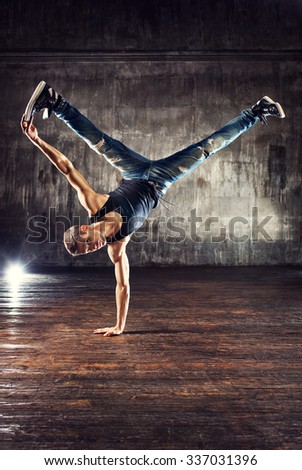 Young man break dancing on old wall background