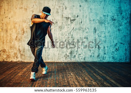 Young man break dancing on wall background. Vibrant colors effect. Tattoo on body.