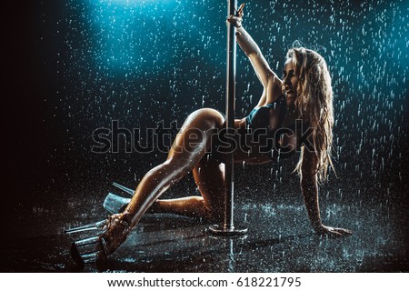 Young sexy slim woman pole dancing with water rain drops