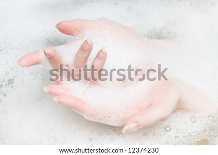 Woman hands in a bath with foam.