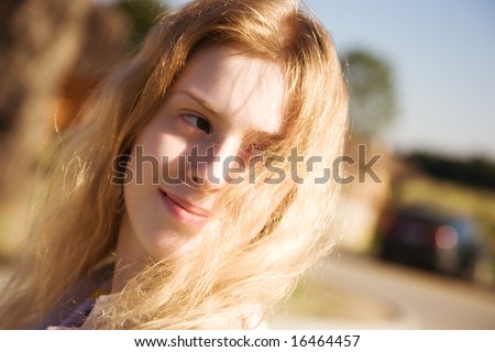 Young woman with fluttering hair outdoors. Focus on hair.