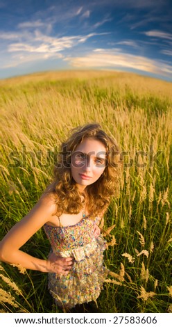 Young woman on a summer field. Wide angle view.
