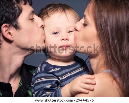 Family portrait. Mother and father kissing their son.