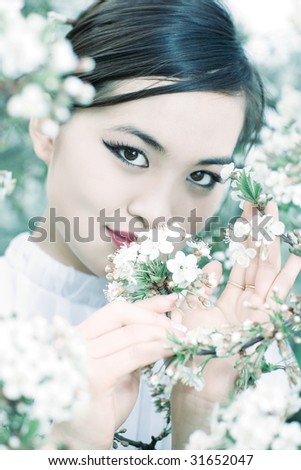 Young woman with cherry flowers portrait. Bright white and cyan tint.