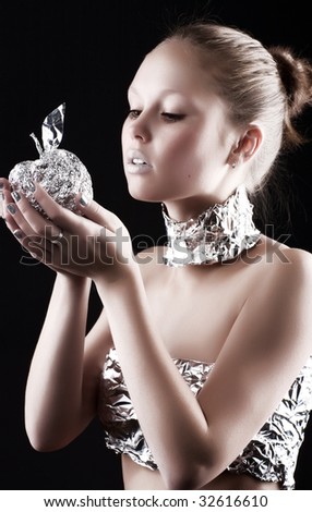 Robot woman with metallic apple. On dark background.