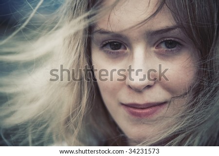 Woman with fluttering hair concept portrait. Soft yellow and blue tint.