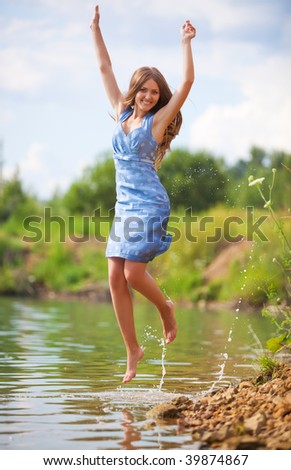 Young woman jumping on a river bank.