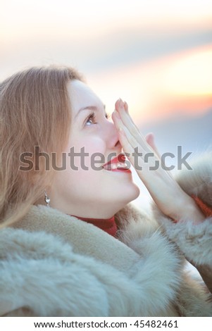 Young woman winter portrait. Rubing her nose.