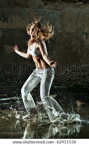 Young woman dancing on street with water.