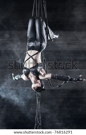Young woman gymnast. On wall background with smoke effect.