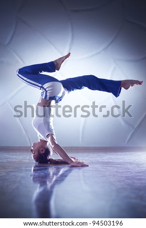 Young woman gymnast. On wall background.