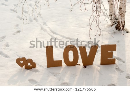 Letters L,O,V,E made from cardboard, placing on the snow between two human trails