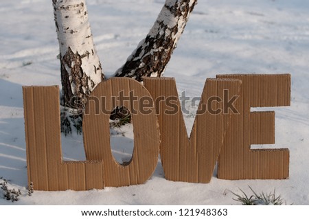 Letters L,O,V,E made from cardboard, placin? on the snow between two human trails
