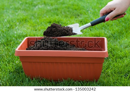 Female hand holding garden shovel with compost- stock photo