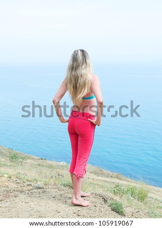cute girl on the shore watching the sea with his hands on his belt