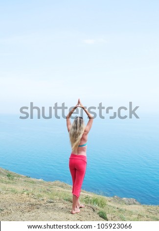 beautiful girl on the shore watching the sea raising his hands in the air
