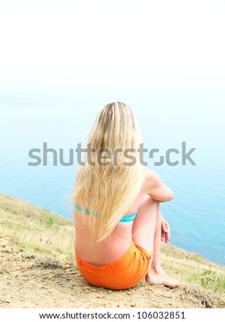 girl sitting on the beach hugging her knees