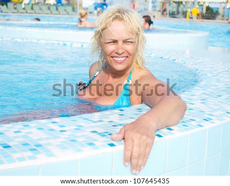 Portrait of an attractive middle-aged woman resting in a pool of blue water in the water park